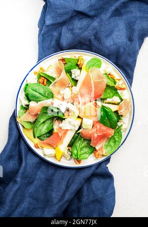 Salade de poires au prosciutto, fromage bleu, épinards, noix sur fond blanc, vue de dessus, espace copie Banque D'Images