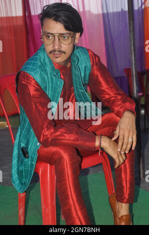 Un jeune homme indien à l'aspect agréable posant avec assis sur une chaise avec du kurta, un pajama, un manteau nehru et des lunettes de soleil avec l'aspect latéral Banque D'Images