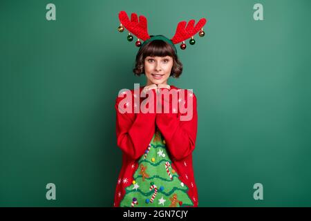 Photo de jeune femme rêveuse excitée porter imprimé chandail cornes bras menton sourire isolé couleur vert fond Banque D'Images