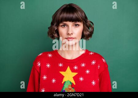 Portrait d'une jolie fille à poil brun portant un pull-over d'hiver festal isolé sur fond vert Banque D'Images