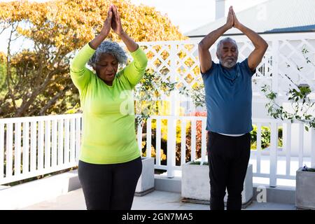 Couple senior afro-américain spécialisé pratiquant le yoga dans le jardin Banque D'Images