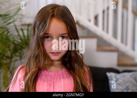 Triste fille caucasienne regardant l'appareil photo à la maison Banque D'Images