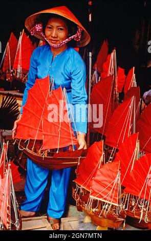 Vietnam. Ho Chi Minh ville. Femme locale dans la boutique de souvenirs artisanaux vendant des junks chinois modèles. Banque D'Images