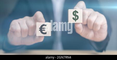 Mains tenant des cubes avec l'icône dollar et euro. Concept de devise. Les mains de l'homme d'affaires tiennent deux cubes de bois avec dollar et euro signe. Homme d'affaires choo Banque D'Images