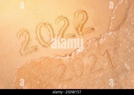 numéro de la nouvelle année écrite dans le sable, sur la plage tropicale. Remplacer les chiffres 2021 par 2022. Vacances du nouvel an sur une île tropicale. La vague de mer lave aw Banque D'Images