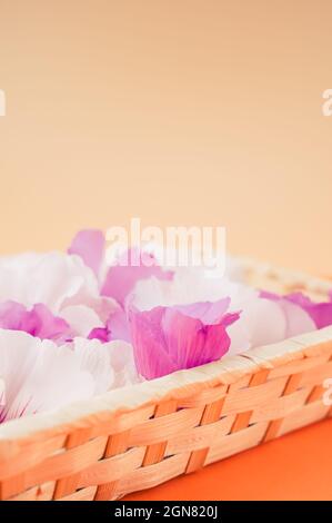 têtes de fleurs d'hibiscus blanches et roses dans un contenant en osier sur une surface orange Banque D'Images
