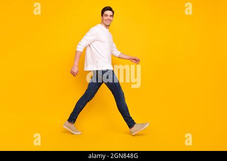 Pleine longueur de corps photo brunet gars souriant confiant marche avant isolé couleur jaune vif fond Banque D'Images