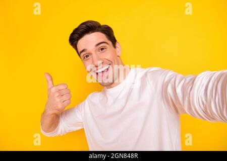 Photo de la funky brunet jeune gars do selfie montrer pouce vers le haut porter chemise isolée sur fond jaune Banque D'Images