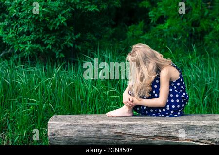 une fille blonde assise sur le banc Banque D'Images