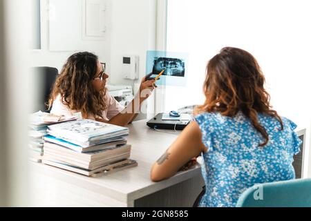 Le dentiste présente des examens radiographiques à l'un de ses patients - concept de bien-être et de prévention dentaire Banque D'Images