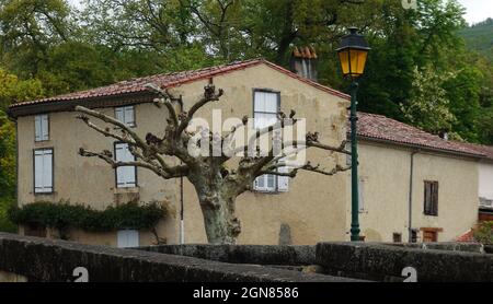 Une lanterne de rue traditionnelle à côté d'un arbre sec et en face d'une maison de campagne, le Mas d'Azil, France Banque D'Images