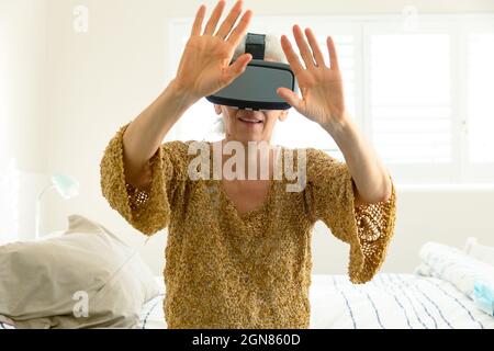 Bonne femme de race blanche, portant un casque vr et s'amusant Banque D'Images