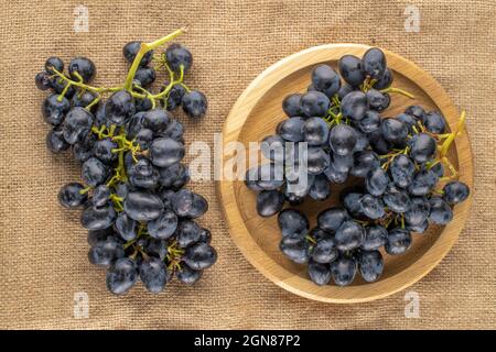 Deux petits pains de raisins noirs doux avec plateau en bois sur toile de jute, vue rapprochée du dessus. Banque D'Images