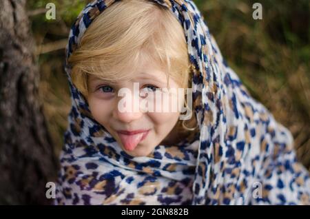 petite fille charmante avec de longs cheveux blonds avec foulard s'amuser dans la forêt d'automne Banque D'Images