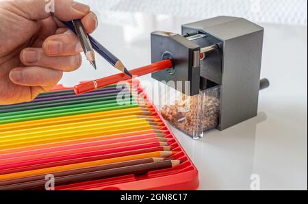 Affûter un ensemble d'artistes professionnels crayons à base de cire d'huile de couleur de qualité dans un aiguiseur mécanique rotatif à un point fin Banque D'Images