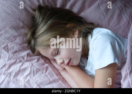 Petite fille dormant dans un lit rose à la maison Banque D'Images