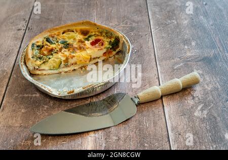 Quiche de légumes méditerranéens maison sur fond de bois avec tranche de gâteau en métal antique sélectionnée Banque D'Images