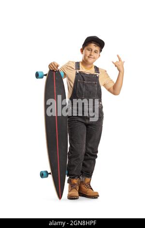 Portrait en pleine longueur d'un garçon froid posant avec une longue planche et faisant gesturer un roc et un panneau de rouleau isolé sur fond blanc Banque D'Images