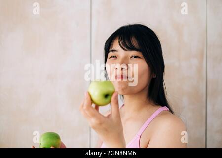 Jeune femme mangeant de la pomme à la maison Banque D'Images