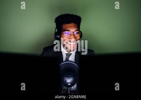 Un homme souriant avec un casque pour la diffusion en direct à la maison Banque D'Images