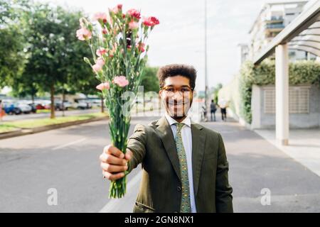 Homme d'affaires heureux montrant un bouquet en se tenant dans la rue Banque D'Images