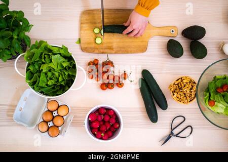 Une femme hache le concombre sur une planche à découper dans la cuisine Banque D'Images