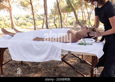 Masseuse femme massante couchée sur une table en forêt Banque D'Images