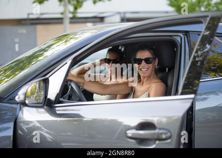 Sœurs jumelles souriantes portant des lunettes de soleil assises en voiture Banque D'Images