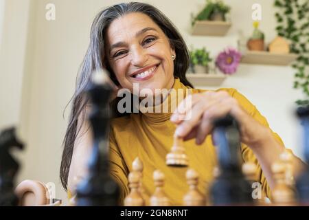 Souriante belle femme jouant aux échecs à la maison Banque D'Images