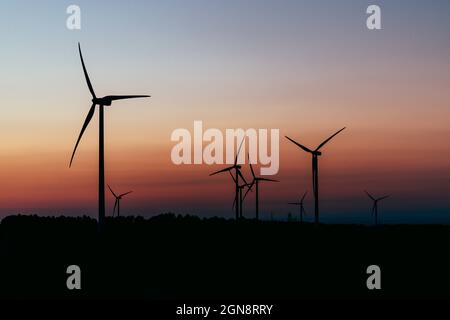 Silhouettes d'éoliennes debout contre le ciel de moody au crépuscule Banque D'Images