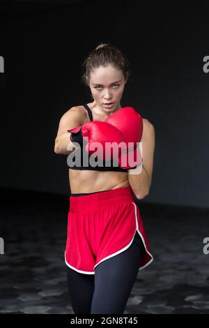 Athlète féminine portant des gants de boxe pratiquant au sous-sol Banque D'Images