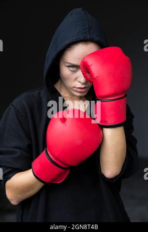 Jeune athlète féminin déterminé en gants de boxe rouges Banque D'Images