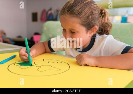 Jolie fille souriante colorant dessin terre à la maison Banque D'Images