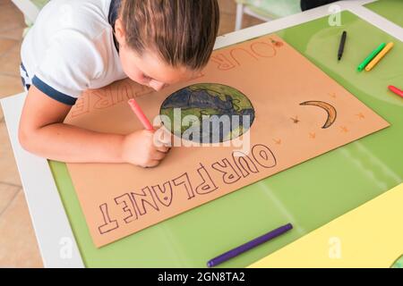 Fille dessin sur papier de carton à la table dans la salle de séjour Banque D'Images