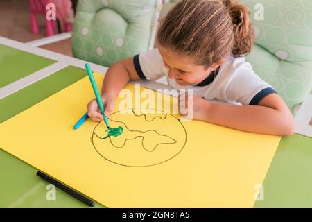 Fille blonde souriante colorant la terre croquis à la maison Banque D'Images