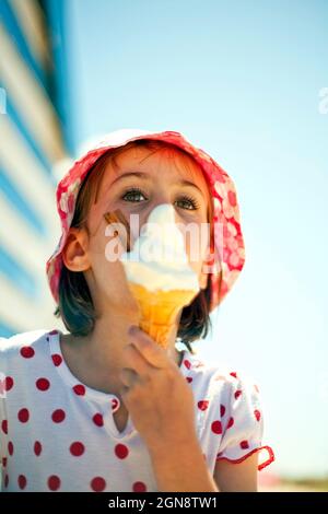 Fille regardant loin tout en mangeant de la crème glacée au soleil Banque D'Images