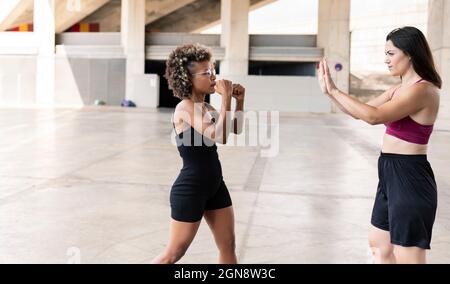 Femme adulte de taille moyenne pratiquant la boxe avec une amie Banque D'Images