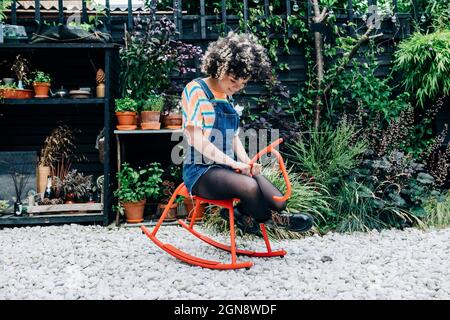 Une femme heureuse assise sur un cheval à bascule à l'arrière-cour Banque D'Images