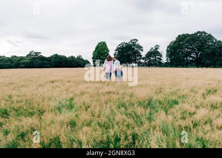 Famille tenant les mains en marchant sur la prairie Banque D'Images