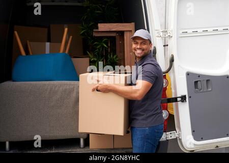 Personne de livraison mâle tenant la boîte en carton près de la camionnette Banque D'Images