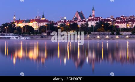 Paysage illuminé de la vieille ville de Varsovie avec le château royal, la cathédrale et les bâtiments médiévaux, vue de nuit avec des reflets dans le calme de la Vistule, Pologne. Banque D'Images