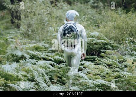 Homme écologiste avec un costume de protection et un sac à dos en verre marchant dans la forêt Banque D'Images