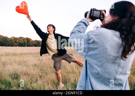 Femme photographiant un homme qui attrape un ballon au parc Banque D'Images