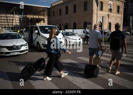 Malaga, Espagne. 23 septembre 2021. Les voyageurs avec des valises sont vus à pied devant un chauffeur de taxi pendant la manifestation.les chauffeurs de taxi ont défilé et bloqué les rues principales de Malaga exigeant un contrôle plus élevé sur les permis de VTC (véhicules avec conducteur). Malaga est la ville d'Andalousie où il y a plus de licences de voitures VTC. Crédit : SOPA Images Limited/Alamy Live News Banque D'Images