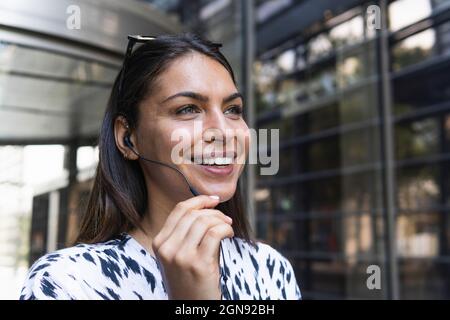 Femme souriante, freelance, parlant au moyen d'un casque Banque D'Images