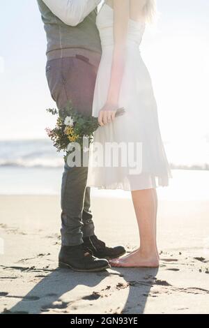 Couple nouvellement mariés debout ensemble sur la plage Banque D'Images