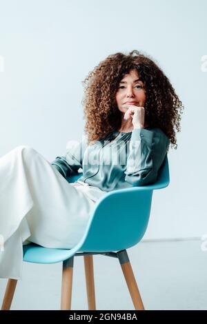 Bonne femme d'affaires avec les mains derrière la tête se détendant au bureau Banque D'Images