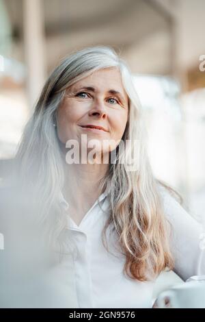 Femme mûre souriante au café Banque D'Images
