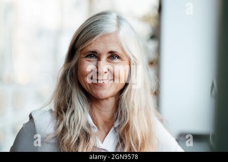 Femme mûre souriante tenant une tasse de café dans un café Banque D'Images