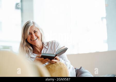 Femme mature lisant le livre tout en étant assise dans un café Banque D'Images
